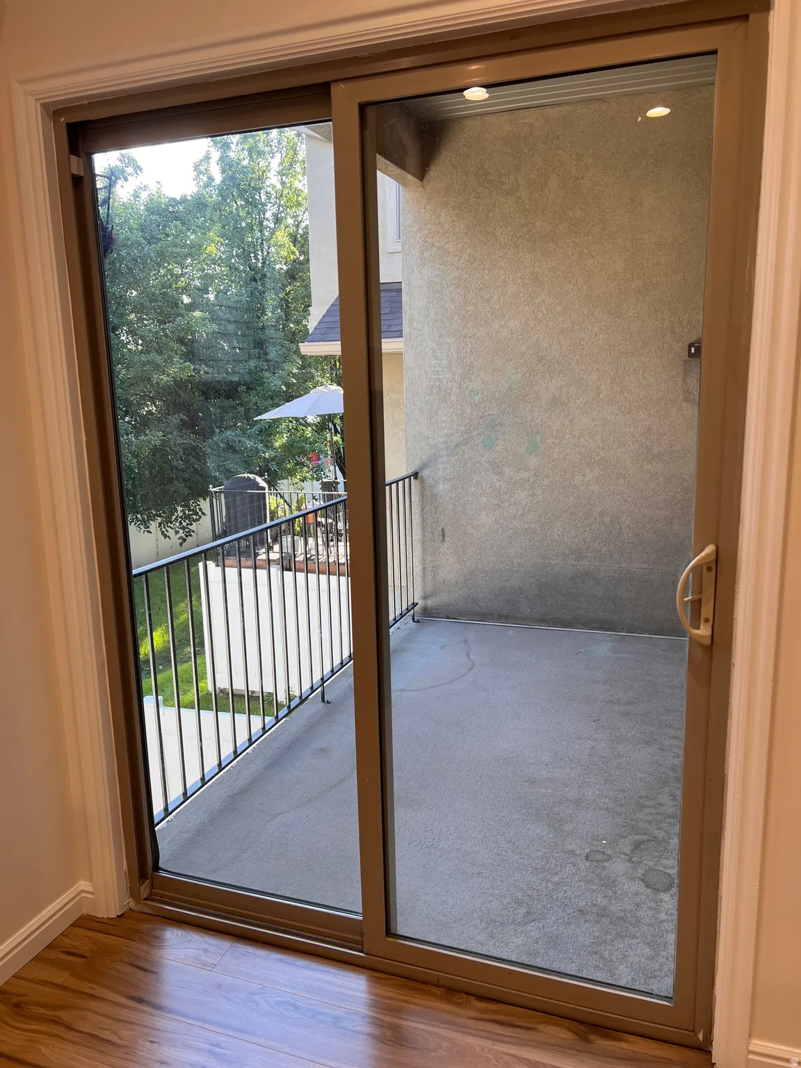 Balcony off living room with sliding glass door, metal railings and a concrete surface