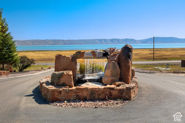 Stone water feature with a flowing waterfall, set against a backdrop of a large body of water and distant mountains