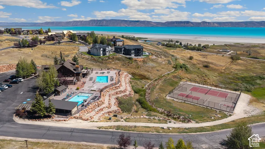 Expansive property featuring two outdoor swimming pools, multiple tennis courts, and surrounding natural landscaping