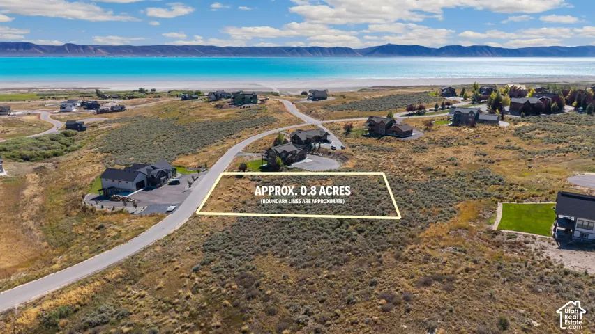 Expansive 0.8-acre lot with potential for construction, surrounded by natural shrubland, and featuring mountain and water scenery