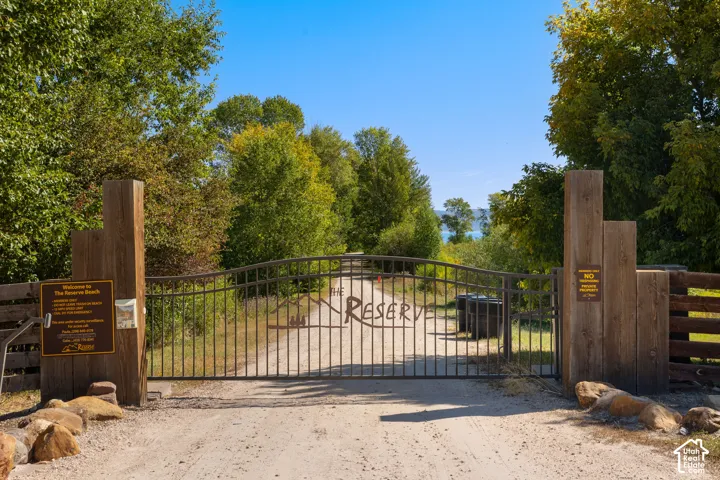 Gated entrance with a gravel driveway, wood posts, and a metal gate