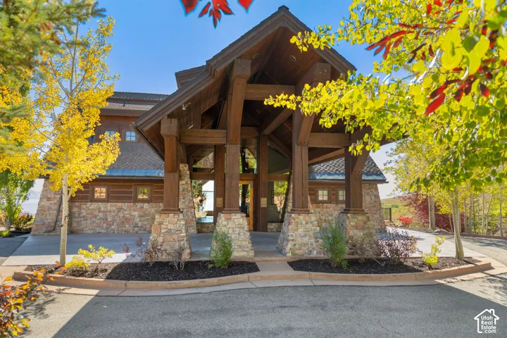 Stone and wood-clad exterior with a covered entry, prominent timber beams, and a paved walkway