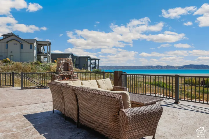 Expansive outdoor patio featuring stamped concrete, a stone fireplace, and a wrought iron railing