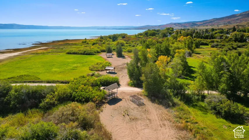 Expansive green spaces and natural landscaping bordering a large body of water, with distant mountains