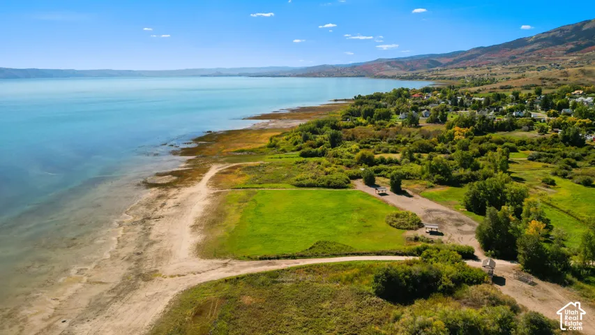 Expansive waterfront property featuring a large grassy area, natural shoreline, and surrounding mature foliage