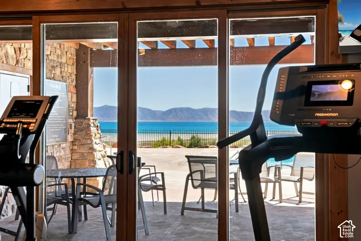 Expansive glass doors open to an outdoor patio with a mountain and water backdrop