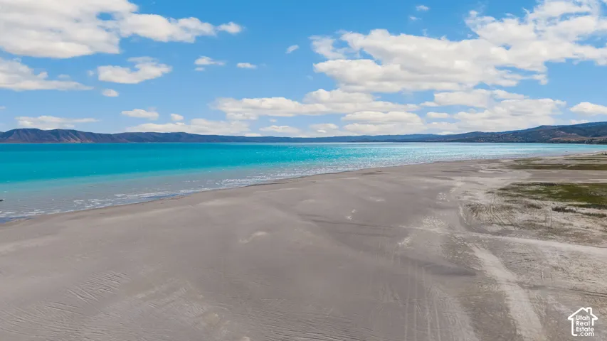 Expansive sandy shoreline with turquoise water and distant mountains