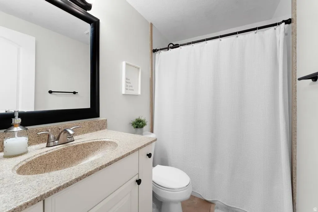 White vanity with cabinet storage, integrated speckled countertop and sink, polished chrome faucet, and a large framed mirror