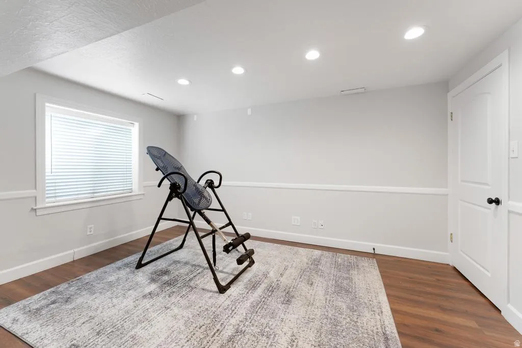 Recessed lighting illuminates the space, featuring wood-finish flooring and a window with blinds