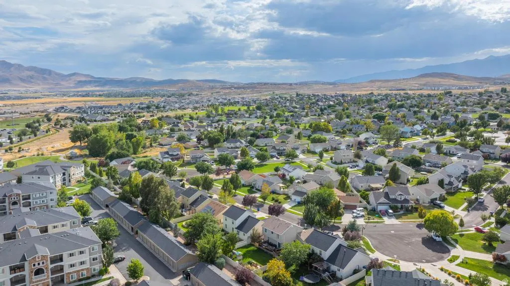 Residential area with single-family homes and multi-story apartment buildings, surrounded by green spaces and distant mountains