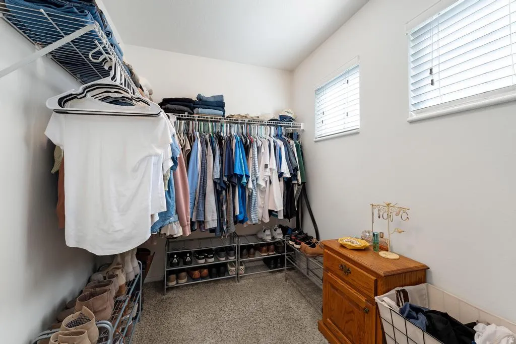 Built-in closet shelving and hanging rods, two windows with blinds, and light-colored walls