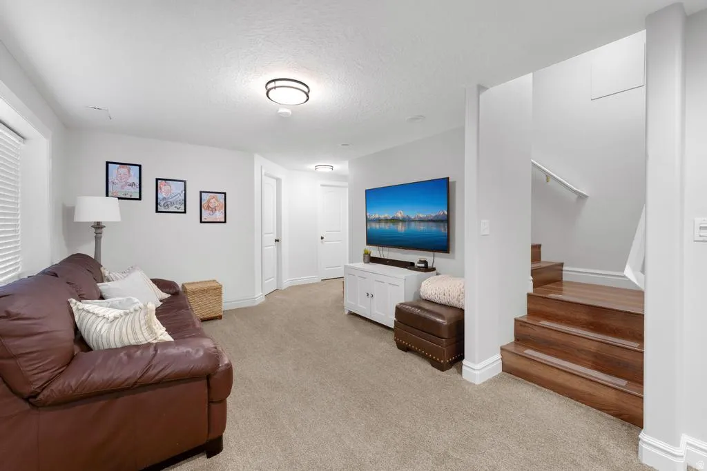 Carpeted flooring, white walls, wood-finish stairs, white trim, and a contemporary flush-mount ceiling light