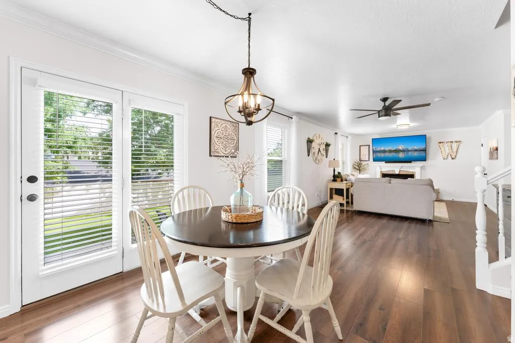 Open-concept living space featuring wood-finish flooring, white walls, and crown molding