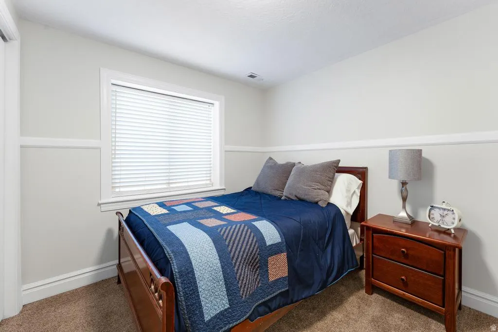 Window with blinds, light-toned walls, and carpeted flooring