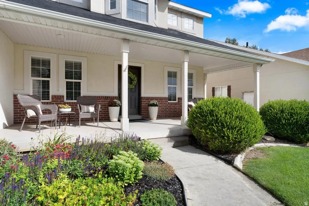 Covered porch with column supports, brick and stucco exterior, dark paneled entry door, and concrete walkway