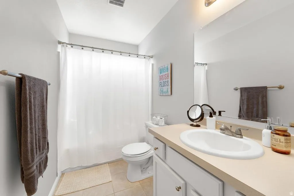 Bathroom featuring a single vanity, integrated sink, and a combination shower/tub with a shower curtain rod