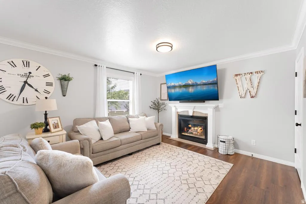 White crown molding, recessed lighting, wood-finish flooring, white window blinds, and a built-in fireplace with a white mantel