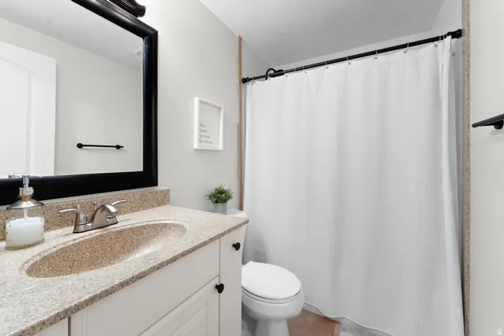 White vanity with cabinet storage, integrated speckled countertop and sink, polished chrome faucet, and a large framed mirror