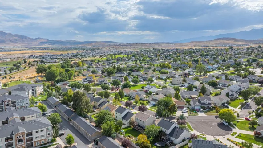 Residential area with single-family homes and multi-story apartment buildings, surrounded by green spaces and distant mountains