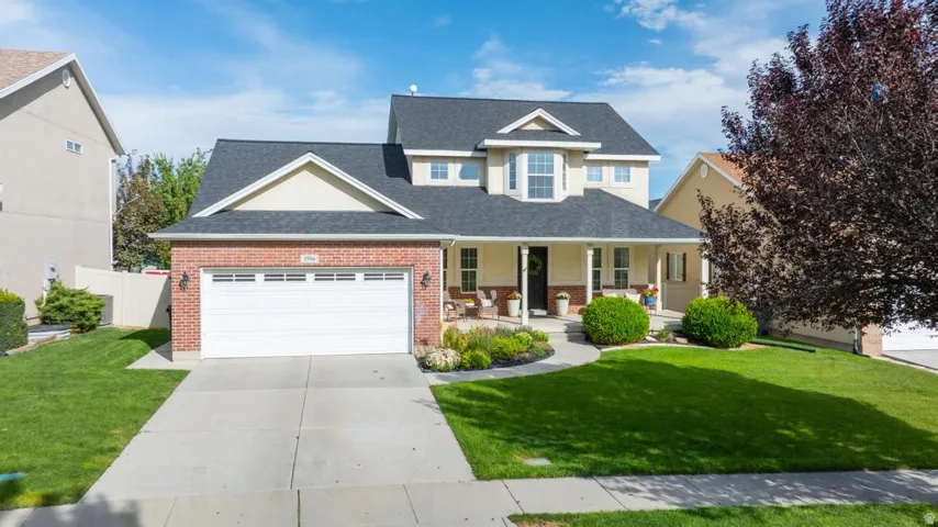 Brick and siding exterior, two-car garage, covered porch, landscaped front yard, and concrete driveway