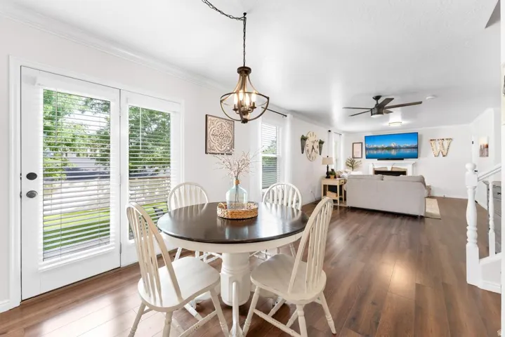 Open-concept living space featuring wood-finish flooring, white walls, and crown molding