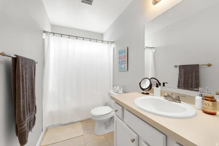 Bathroom featuring a single vanity, integrated sink, and a combination shower/tub with a shower curtain rod