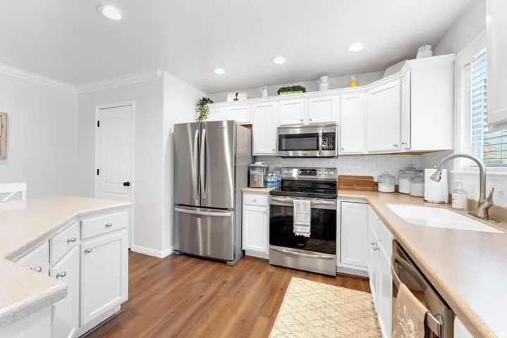 Kitchen featuring white shaker-style cabinetry, wood-finish flooring, stainless steel appliances, and a kitchen island with storage