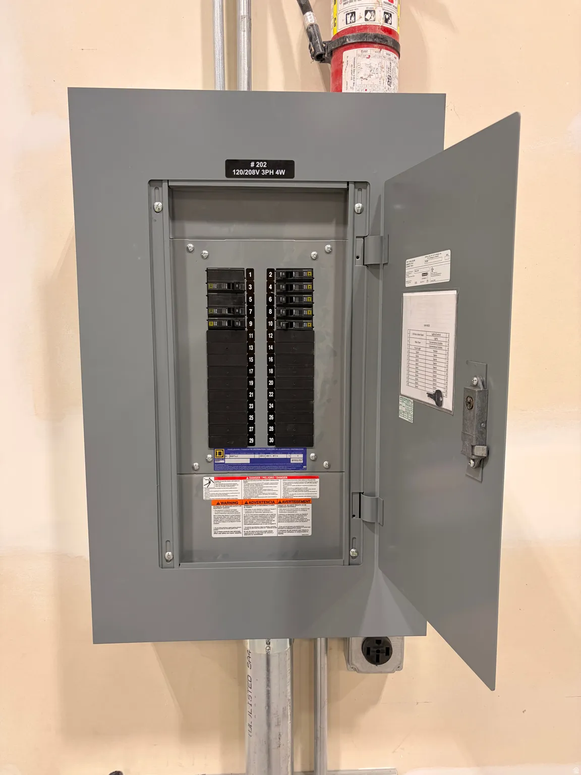 Electrical service panel with an open door, displaying circuit breakers and internal labeling