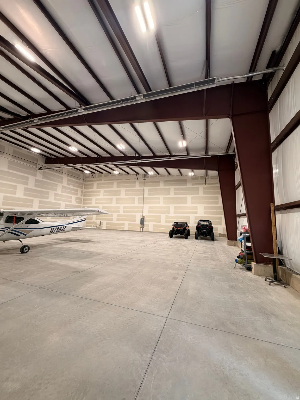 Spacious interior featuring a concrete floor, exposed structural steel beams, and insulated panel ceiling
