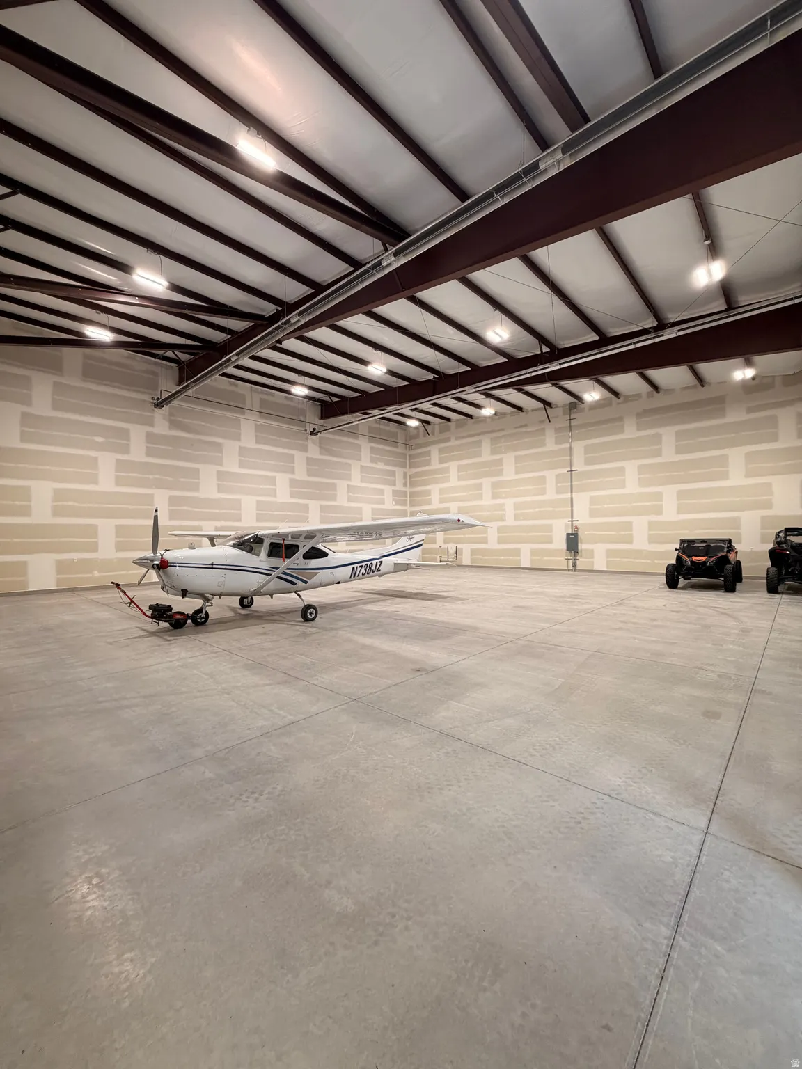 Spacious hangar featuring a concrete floor, exposed metal beam construction, and overhead lighting