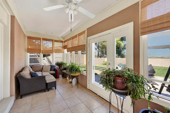 Enclosed sunroom featuring multiple windows, ceiling fan, and tile flooring
