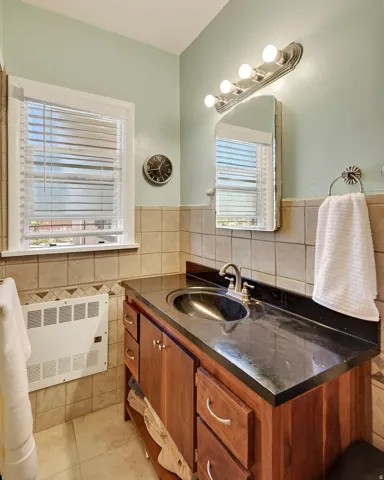 Wood-finish vanity with an integrated basin, dark countertop, and brushed nickel faucet