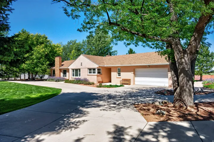 Stucco exterior with a shingle roof, attached two-car garage, and a brick chimney
