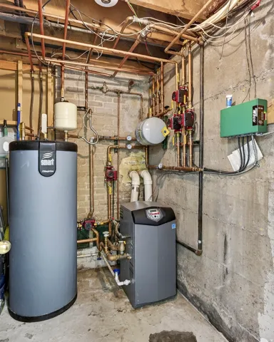 Dedicated mechanical room featuring a water heater, boiler system, and extensive copper piping