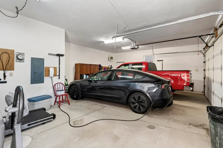 Spacious garage with overhead lighting, concrete flooring, and an electric vehicle charging station