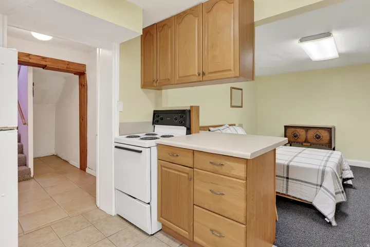 Wood-finish cabinetry, countertop island, white freestanding range, recessed lighting, and tile flooring