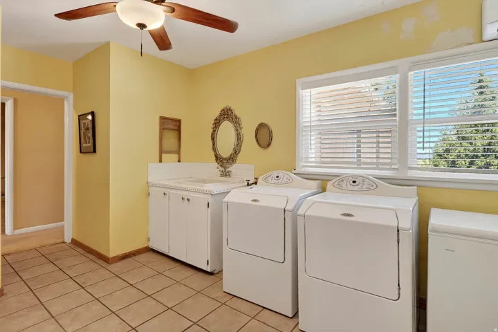 Tiled flooring with white cabinetry and a utility sink