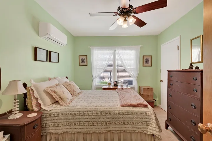 Ceiling fan with integrated lighting, wall-mounted climate control unit, window with blinds, paneled interior door, and a built-in closet