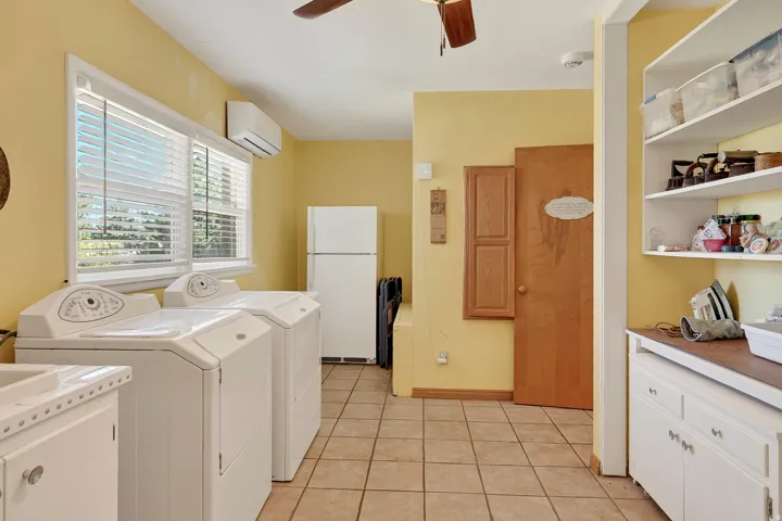Tile flooring, multiple windows with blinds, built-in shelving, white cabinetry, and a ceiling fan