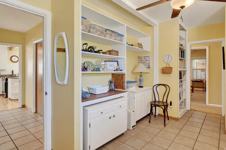 Built-in shelving, tile flooring, wood-finish ceiling fan, recessed built-in shelving, and white cabinetry