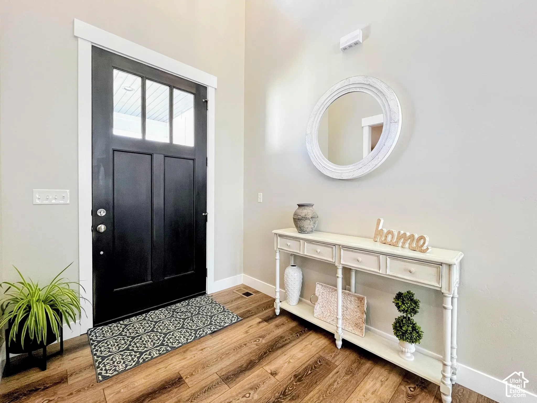 Entryway featuring wood-finish flooring, a black paneled door with glass inserts, and light-toned wall paint