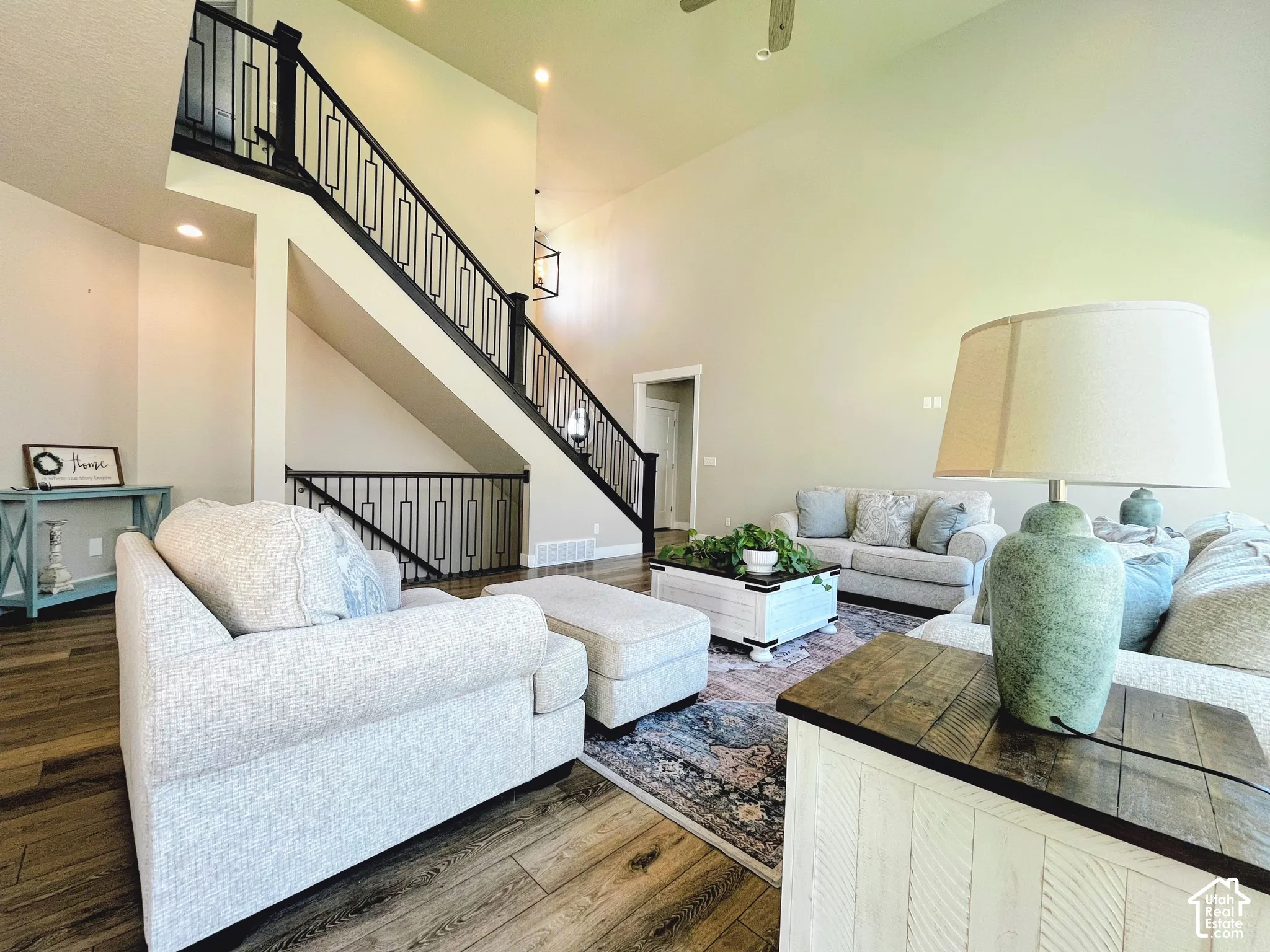 Vaulted ceilings, wood-finish flooring, staircase with custom metal railing, recessed lighting, and a contemporary chandelier