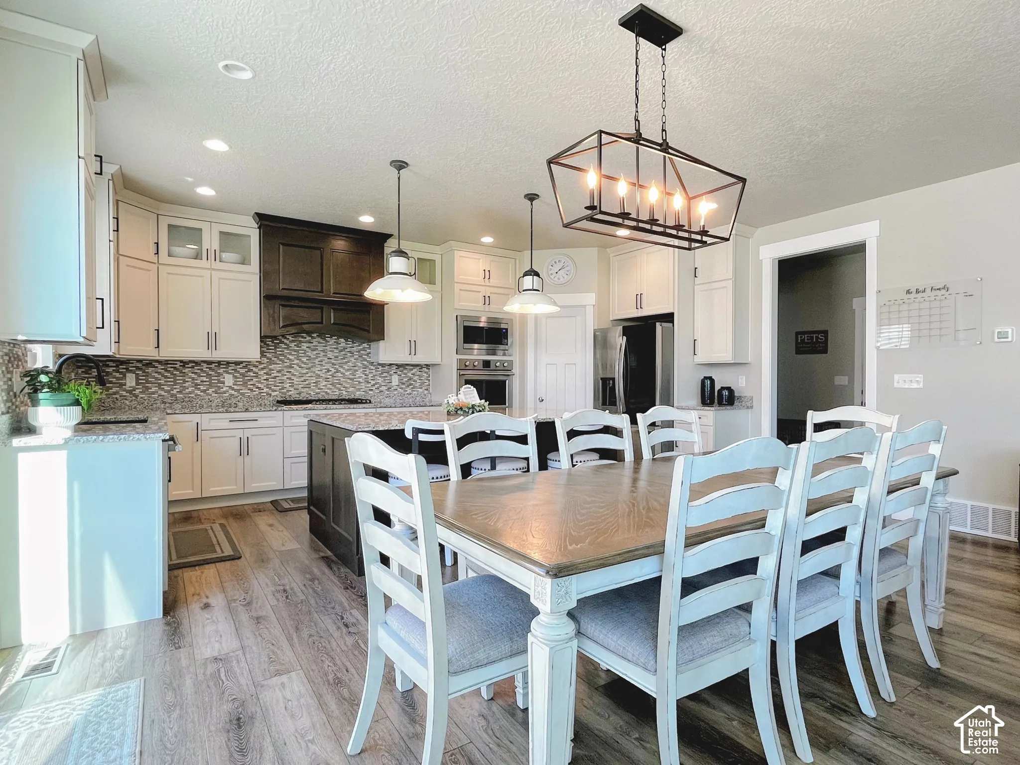 Spacious kitchen and dining area featuring wood-finish flooring, two-tone cabinetry, a large kitchen island, and recessed lighting
