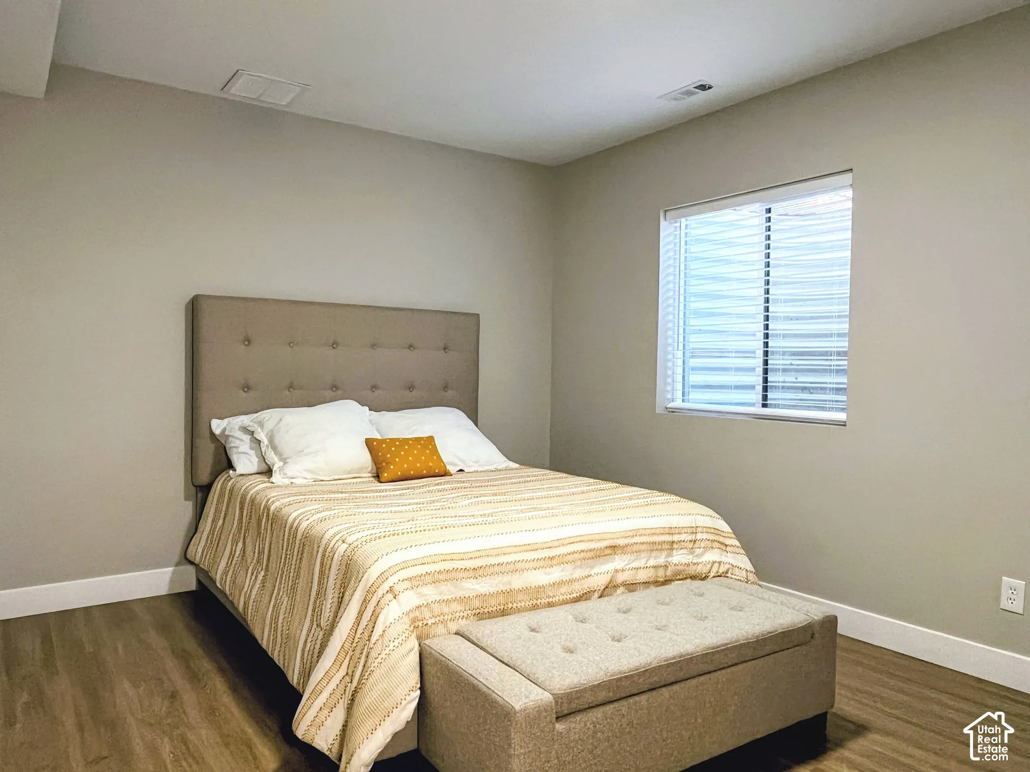 Wood-finish flooring, neutral wall paint, and a window with blinds