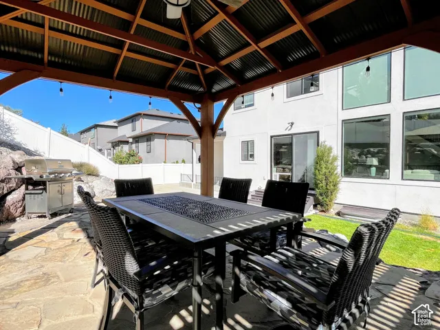 Covered outdoor patio with stone paver flooring, wood-beamed gazebo, and integrated lighting