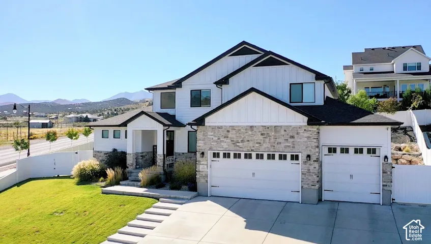 Contemporary architectural style featuring white vertical siding, light-toned stone veneer accents, and a dark shingle roof
