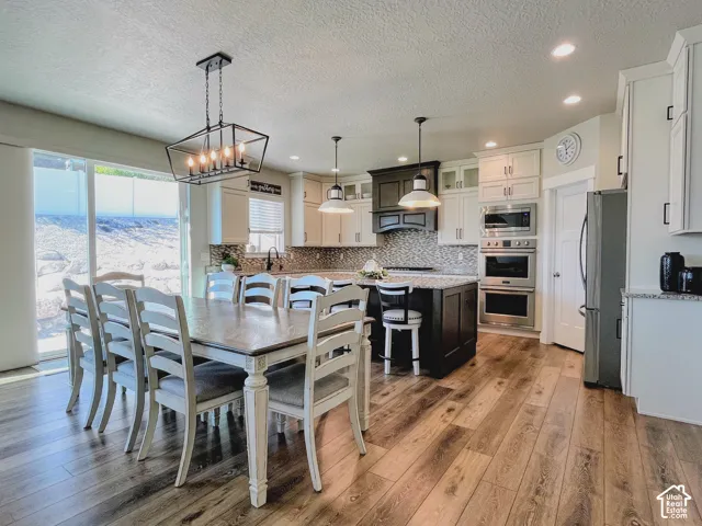 Spacious kitchen featuring wood-finish flooring, two-tone cabinetry, a central island, and stainless steel appliances