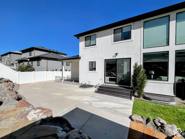 White stucco exterior with black-framed windows and a large concrete patio