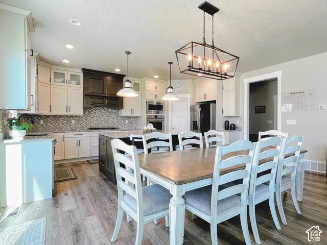Spacious kitchen and dining area featuring wood-finish flooring, two-tone cabinetry, a large kitchen island, and recessed lighting