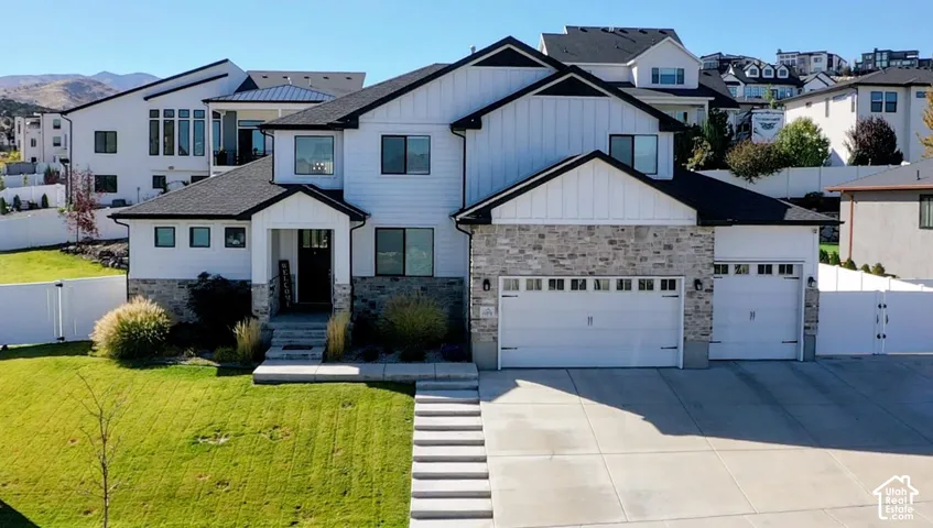 Contemporary exterior with a stone veneer and white siding, featuring a two-car garage, an additional single-car garage, and a multi-level concrete walkway leading to the front entry